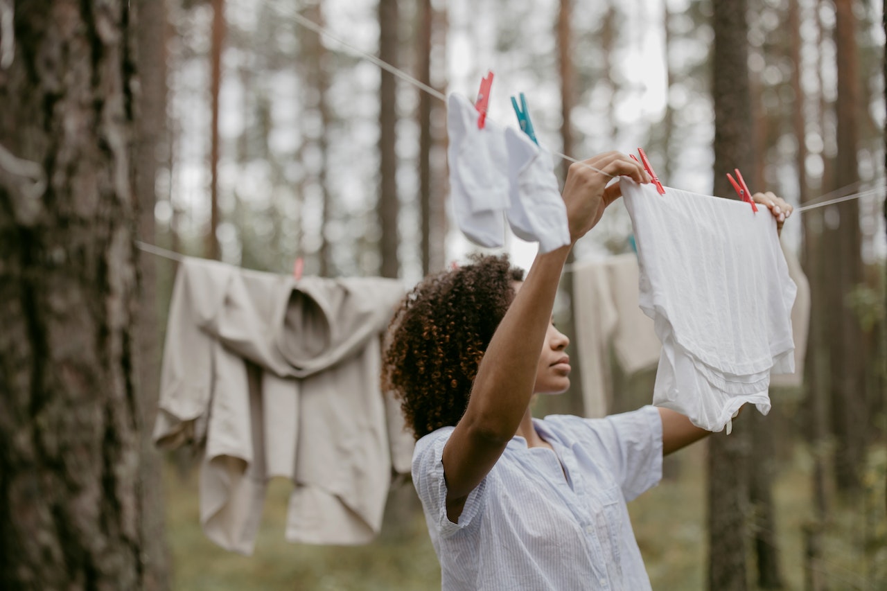 Frau in weißem T-Shirt hängt in Natur Wäsche auf