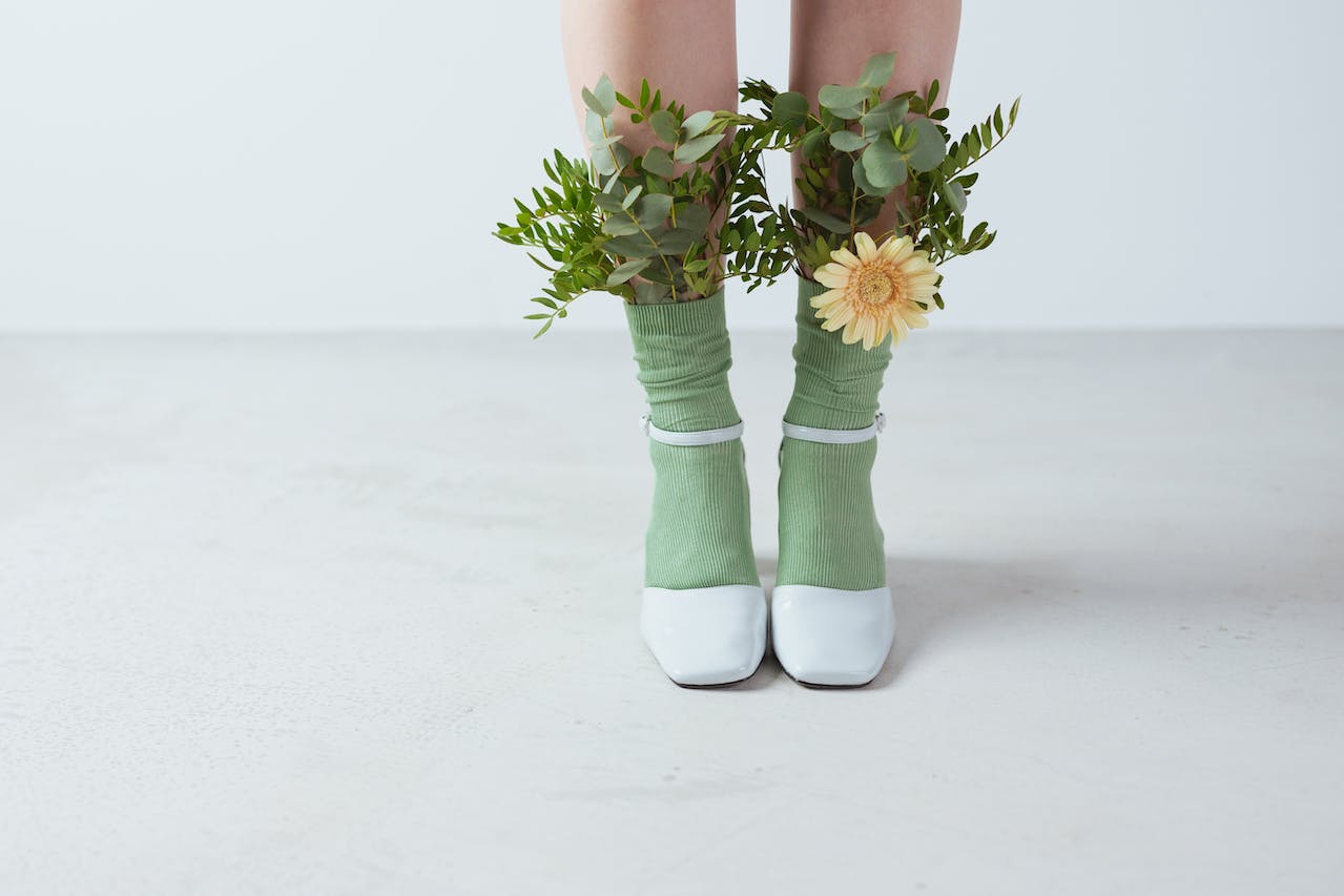Frauenbeine in Schuhen und Socken mit Blumen 