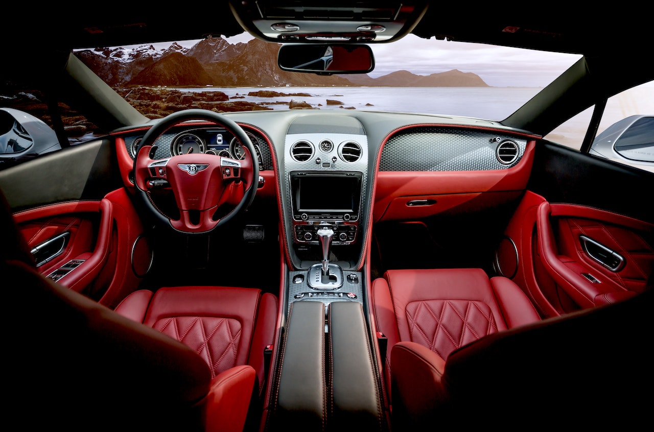 Autoinnenraum mit grauem Cockpit, schwarzem Lenkrad und roten Ledersitzen