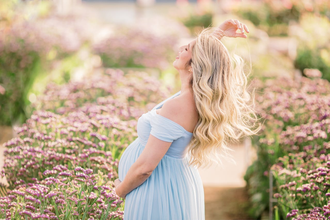 Schwangere blonde Frau im blauen Sommerkleid im Lavendelfeld
