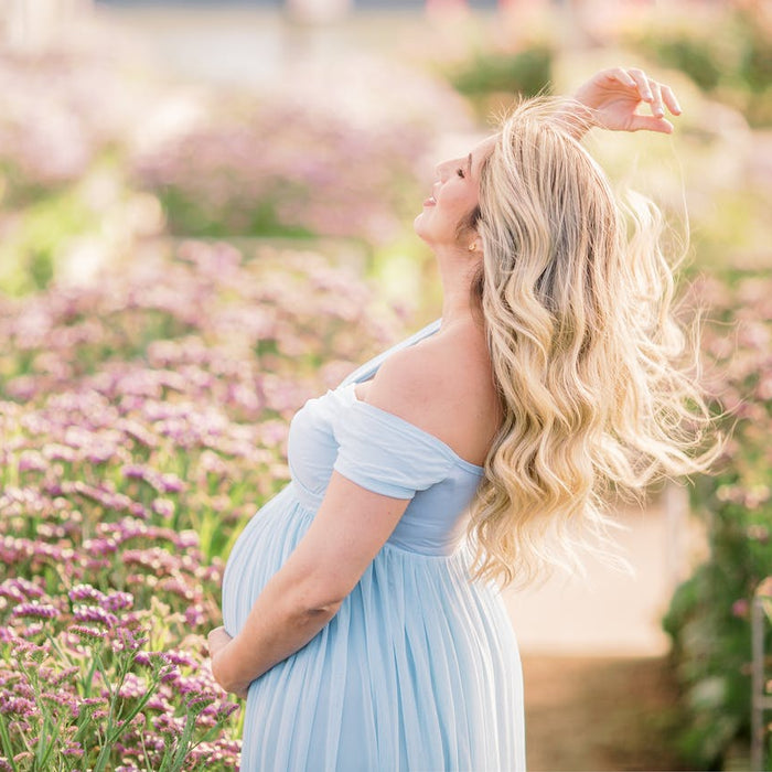 Schwangere blonde Frau im blauen Sommerkleid im Lavendelfeld